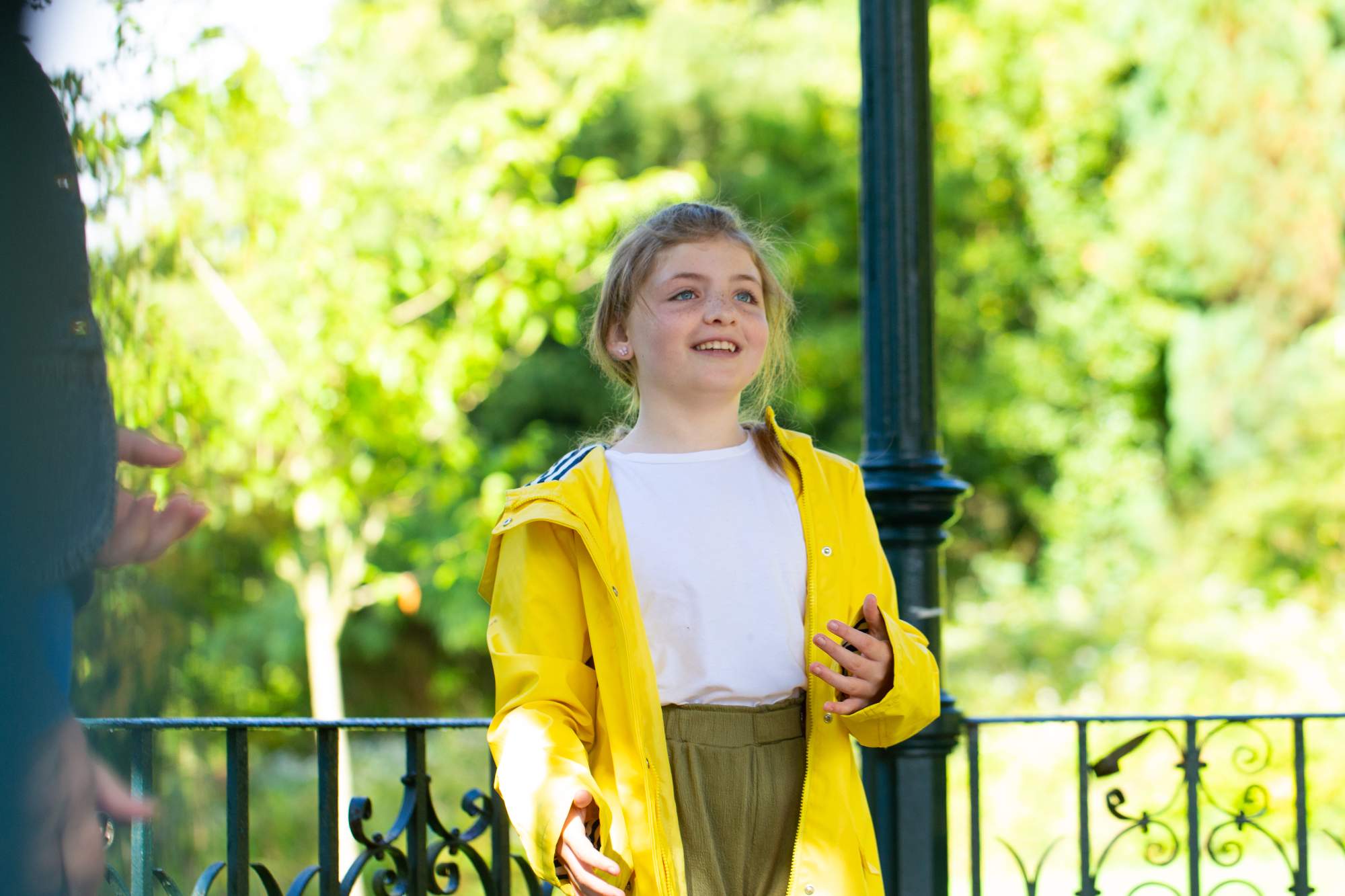 A young girl in a yellow raincoat smiling